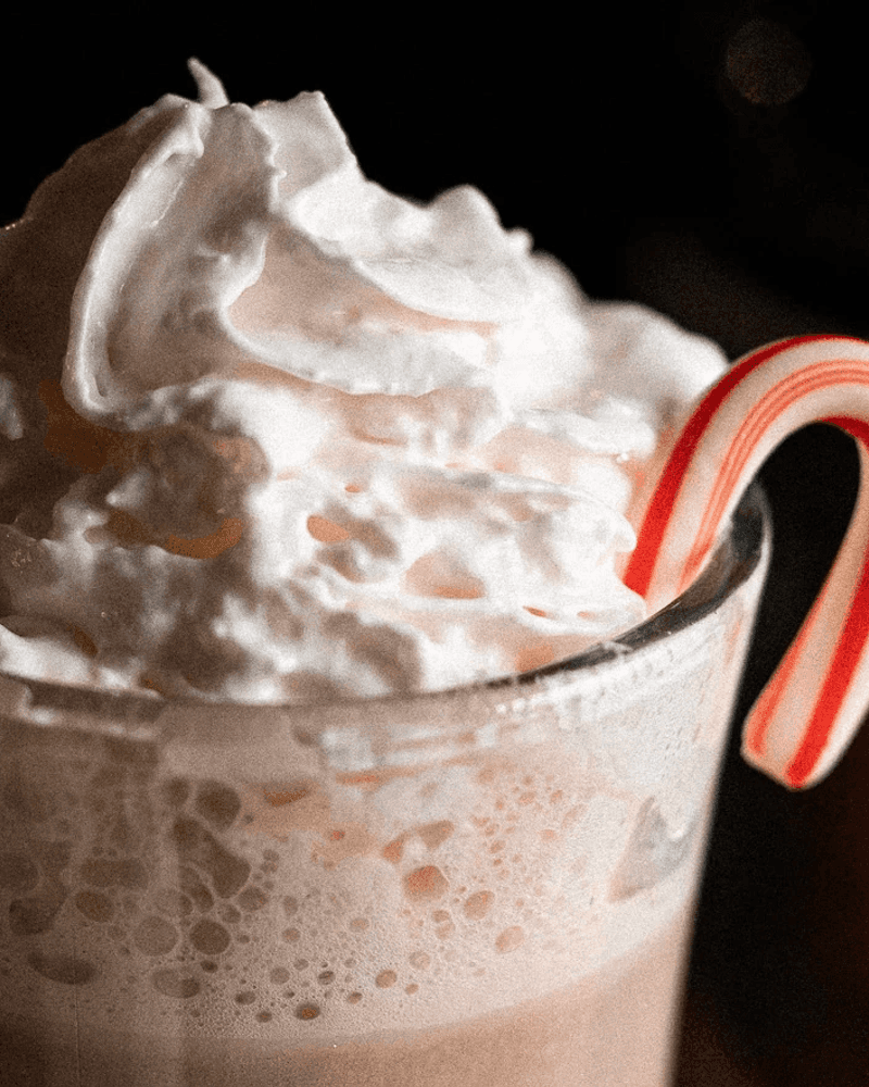 Cocoa powder being dusted across the surface of a Candy Cane Cocoa.