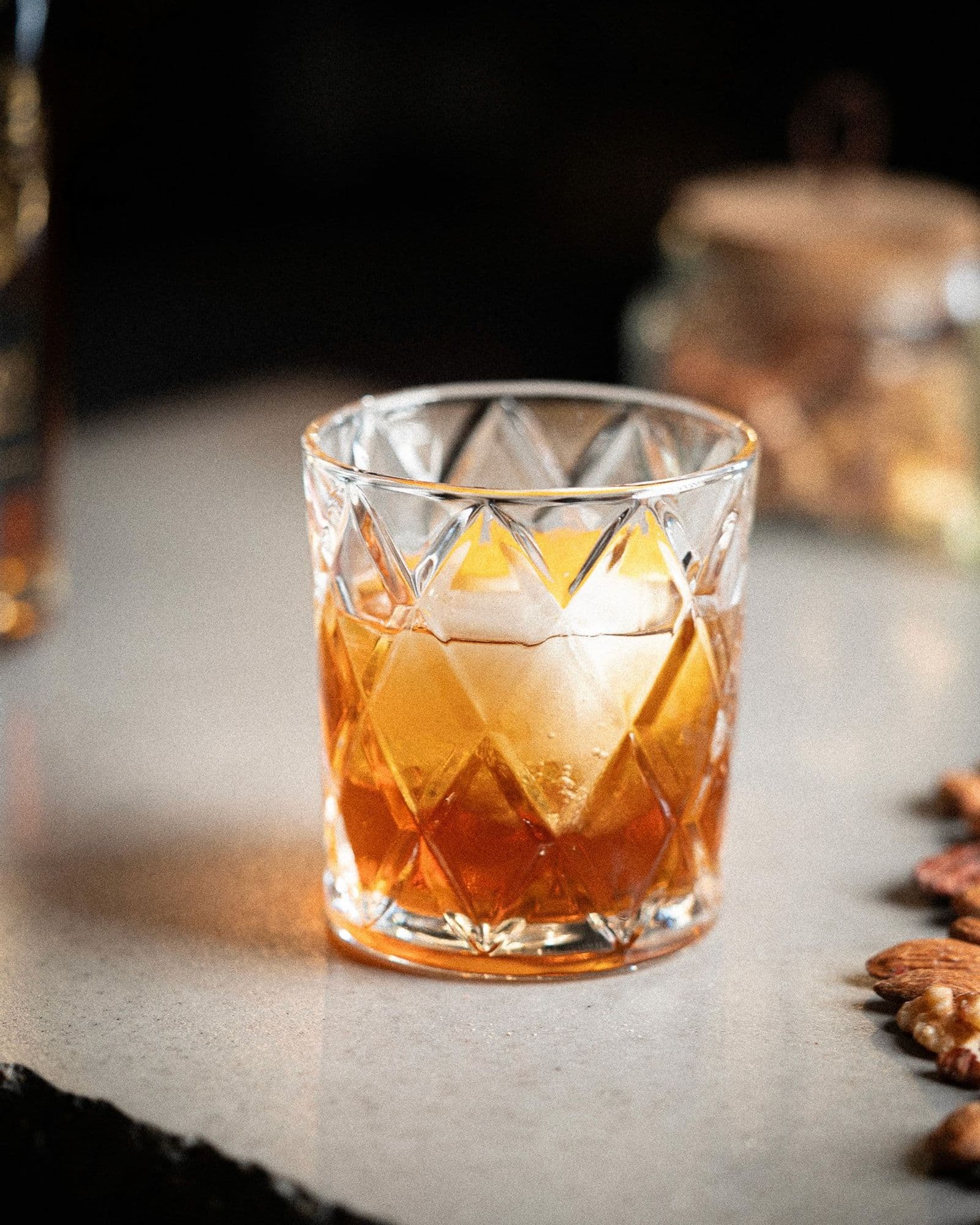 Old-Fashioned Christmas in a double-rocks glass over one large clear cube, expressed orange peel resting on the surface.